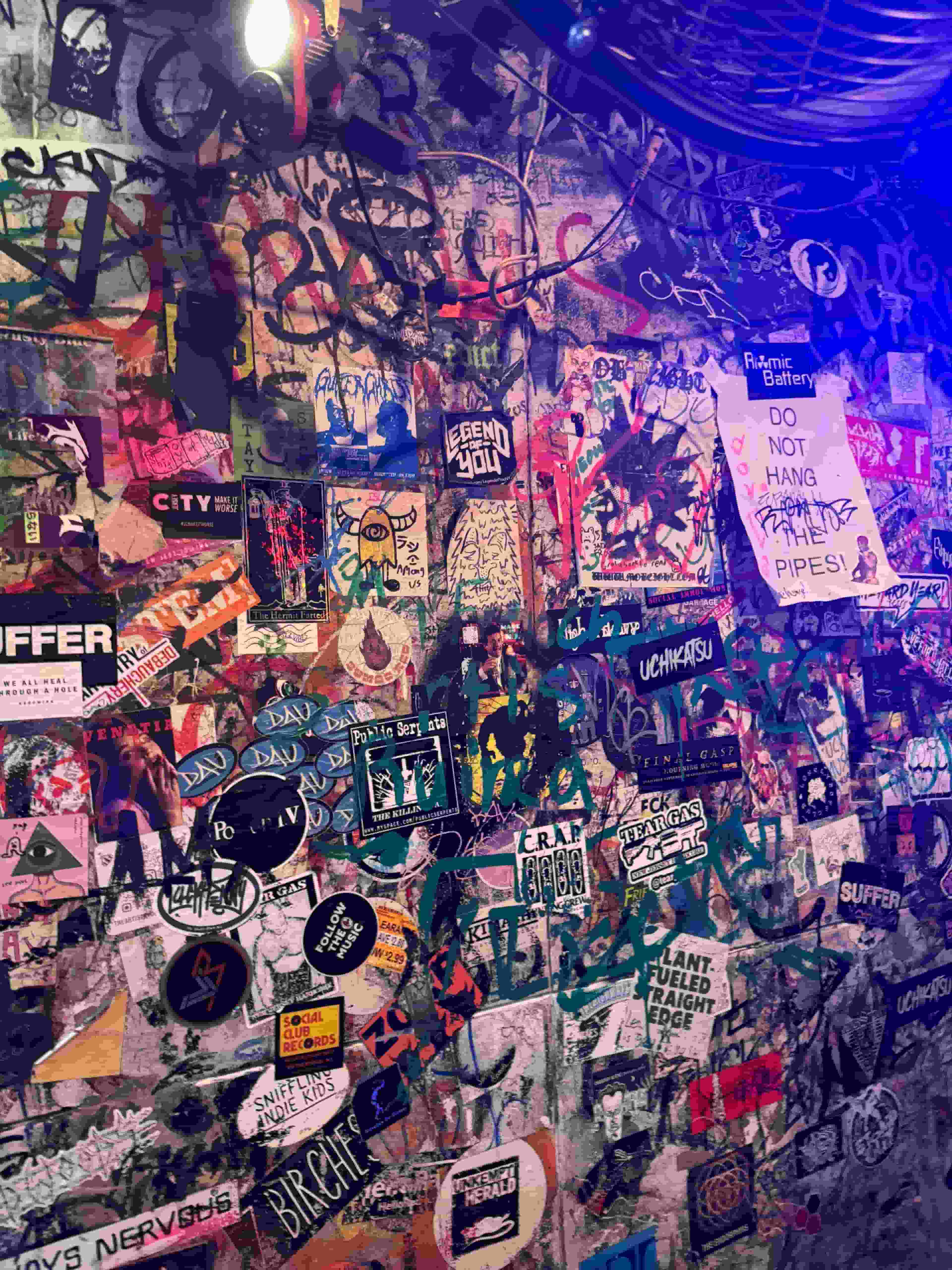 a photo of a wall with a bunch of diferent stickers and graffitti